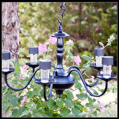 a black chandelier hanging from a tree with pink flowers in the foreground