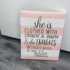 a pink and white sign that says she is clothed with strength & plenty