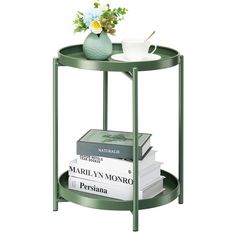 a green table with books and a vase on top, sitting next to each other