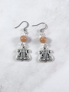 These Apollo earrings are the perfect accessory to show your love for the Greek gods in a subtle way! Made with sunstone gemstone and a lyre charm. Made with fishhook style earrings. I offer both a standard and hypoallergenic option for the hooks. The standard is stainless steel and the hypoallergenic is 925 sterling silver plated. Ships in a jewelry box so it's ready to be give as a gift. All materials are lead and nickel free. Charm is made with zinc alloy. Earrings will be disinfected before Apollo Jewelry, God Greek Mythology, Greek Mythology Jewelry, The Greek Gods, Mythology Jewelry, High Characters, Owl Earrings, Greek God, Alloy Earrings