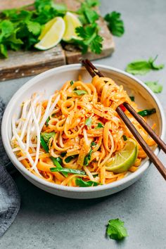 the best vegan pad thai noodles in a white bowl with chopsticks and cilantro