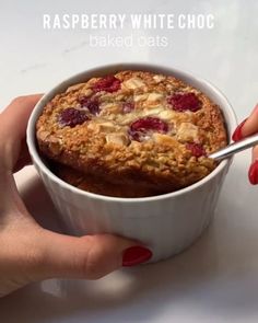 a hand holding a bowl of raspberry white choc baked oats