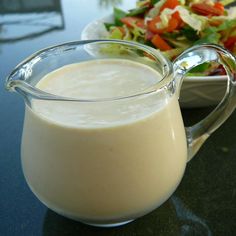 a glass pitcher filled with liquid next to a bowl of salad