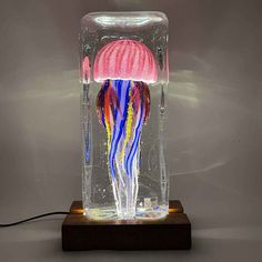 a jellyfish in a glass vase with an electric light on it's side