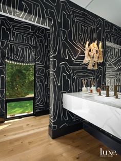 a bathroom with black and white wallpaper, two sinks and large mirrors on the wall