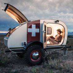 a woman sitting in the open door of a camper trailer