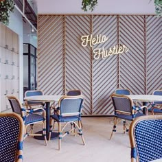 the interior of a restaurant with blue chairs and white tables in front of a wood paneled wall