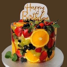 a birthday cake decorated with fruit and the words happy birthday