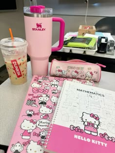 a pink hello kitty notebook and cup on a table