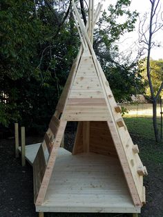 a wooden teepee sitting in the middle of a park