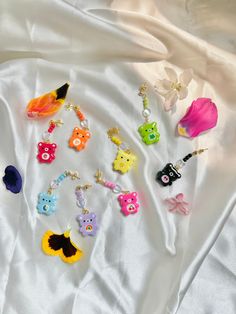 several different colored earrings laying on top of a white sheet with flowers in the background