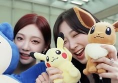 two women holding stuffed animals and smiling at the camera