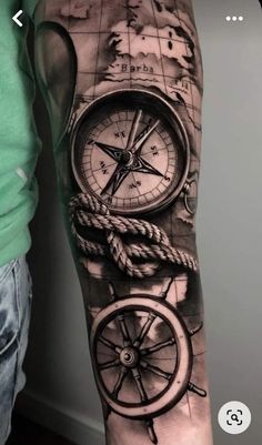 a man's arm with a compass and ship wheel tattoo on the left forearm