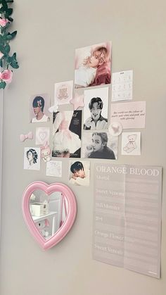 a refrigerator with magnets and pictures on the wall next to a pink heart shaped mirror