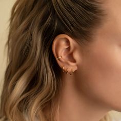 a close up of a woman's ear wearing gold earrings