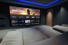 a large screen in the middle of a room with two couches and a flat screen tv