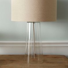 a lamp that is sitting on top of a wooden table in front of a wall