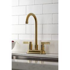 a golden faucet on a white tiled kitchen counter