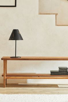 a wooden table with a lamp on it in front of some stairs and a clock