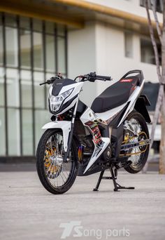 a white and black motorcycle parked in front of a tall building next to a tree