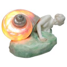 a statue of a person laying on a rock with a shell