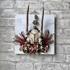 a piece of art made out of wood with horns, flowers and rocks on it