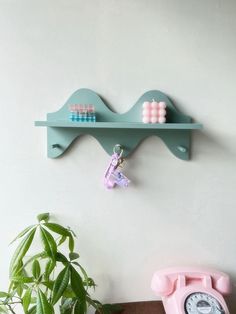 a green shelf with two pink telephones on it next to a potted plant