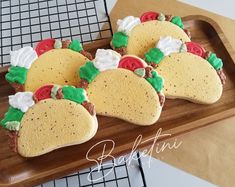 some tacos are sitting on a wooden platter with white and green icing