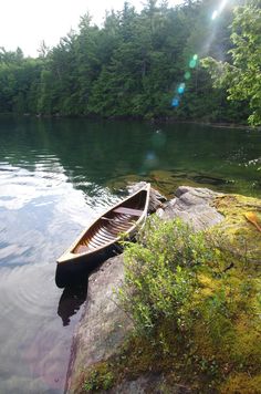 a canoe sitting on top of a rock near the water