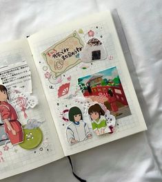 an open book with stickers on the pages and some paper cutouts in it