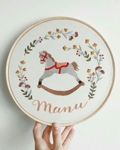 someone is holding up a embroidery kit with a rocking horse on it and the word mama written in cursive font