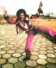 a man in pink pants and jacket doing a trick with his hands out to the side