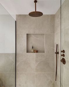 a bathroom with a walk in shower next to a tiled wall and wooden handles on the door