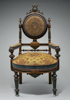 an antique chair with ornately decorated upholstered back and arm rests against a gray background