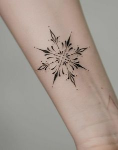 a small black and white tattoo on the wrist, with an intricate flower in the center