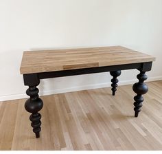 a wooden table sitting on top of a hard wood floor next to a white wall