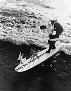 an old black and white photo of santa claus riding a surfboard with reindeers on it