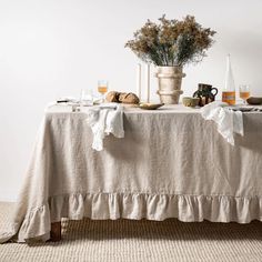 the table is set with bread, wine glasses and flowers in vases on it