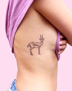 a woman's stomach with a small tattoo of a deer on the bottom side