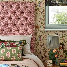 a bedroom with floral wallpaper and pink bedding in front of a large window