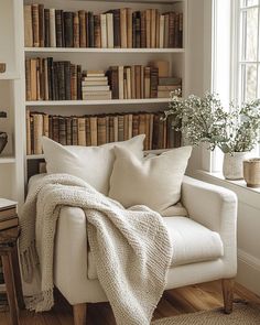 a white chair sitting in front of a book shelf filled with books