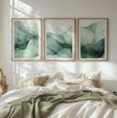 three paintings hanging on the wall above a bed