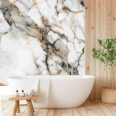 a white bathtub sitting next to a wooden wall with gold leafy decorations on it