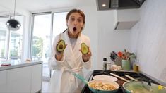 a woman holding an avocado in front of her face and making a surprised face