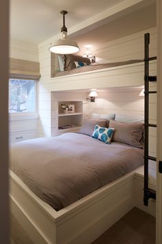 there is a bed that has been made up in the room with two shelves above it