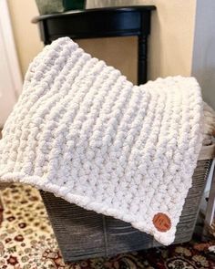 a white crocheted blanket sitting on top of a wooden crate next to a chair