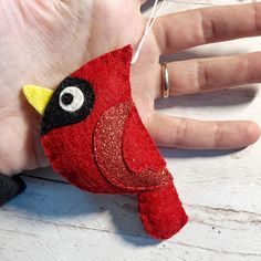 a hand holding a red felt bird ornament