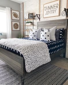 a bed with black and white pillows on top of it next to a brick wall