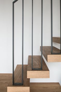 some wooden steps with metal railings in a white walled room and wood flooring