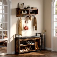 a wooden bench sitting under a window next to a coat rack